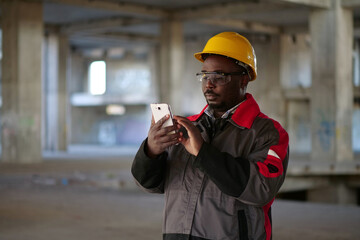 African american workman with smartphone at construction site