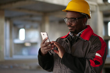 African american workman with smartphone at construction site