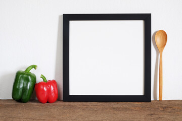 black frame picture with bell peper and wooden spoon on shelf