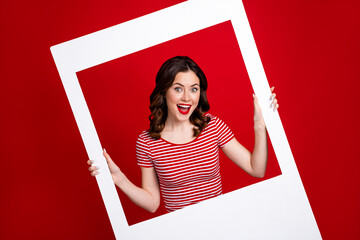 Funny lady photographing through big white paper frame cadre popular photo zone wear striped top...