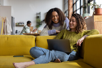 Students in a house share looking at a laptop together smiling