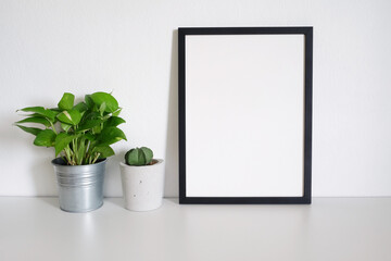 blank frame picture with plants on table in room