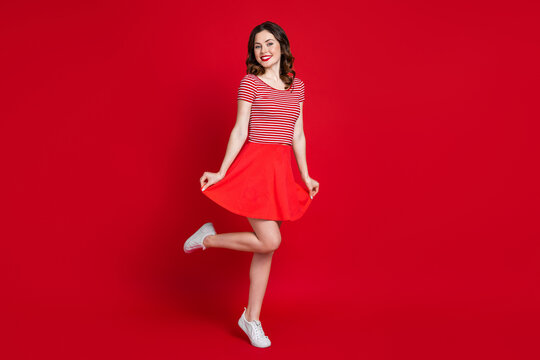 Full body photo of cute girl stand tip toe show new skirt shopping season wear top gumshoes isolated red color background