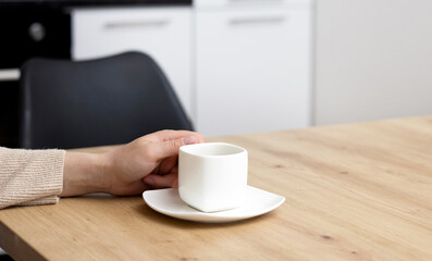 Fototapeta na wymiar woman drinking coffee and using tablet pad sitting at kitchen table modern home house interior.close up white cup sugar holder. female order something online,shopping at home,sales,delivery concept.