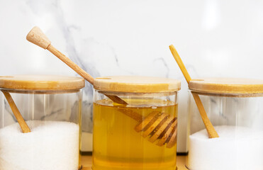 glass jars with salt sugar and honey in. modern kitchen interior,table.wooden spoon honey long...