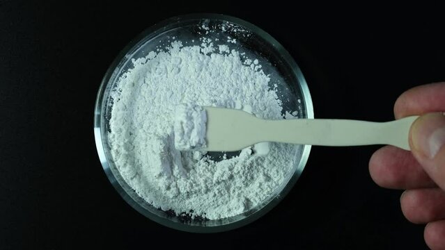 Titanium dioxide, TiO2. White chemical powder in Petri dish. Food additive E171. Titanium dioxide used in cosmetic and skin care products, used also as pigment and thickener.