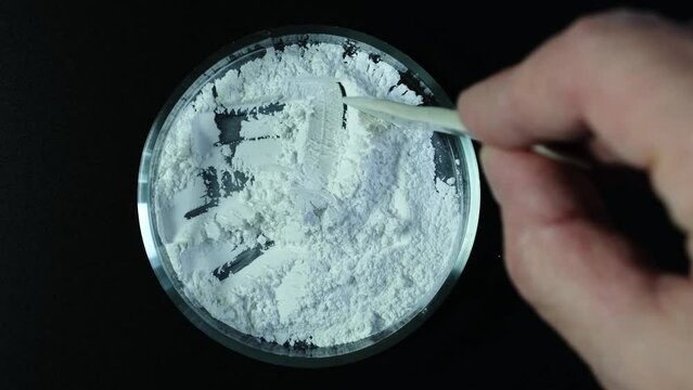 Titanium dioxide, TiO2 in Petri dish, top view. White chemical powder. Food additive E171. Titanium dioxide used in cosmetic and skin care products.