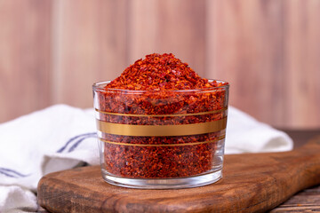 Red chili flakes. Crushed chili pepper or dried chili flakes in glass bowl on wood background