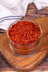 Red chili flakes. Crushed chili pepper or dried chili flakes in glass bowl on wood background