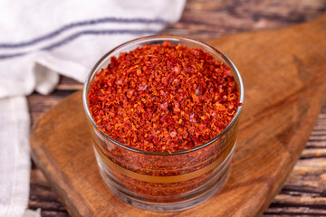 Red chili flakes. Crushed chili pepper or dried chili flakes in glass bowl on wood background. Close up