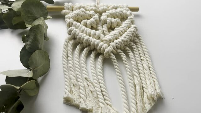 Macram&eacute; wall hanging,  with heart pattern. close up. Slow motion shot. macrame pattern from natural white cotton threads. 
