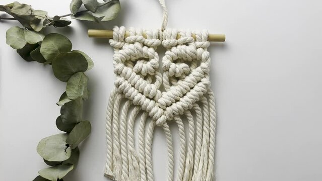 Macram&eacute; wall hanging,  with heart pattern. close up. Slow motion shot. macrame pattern from natural white cotton threads. 