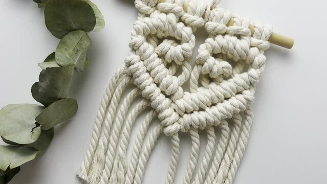 Macram&eacute; wall hanging,  with heart pattern. close up. Slow motion shot. macrame pattern from natural white cotton threads. 