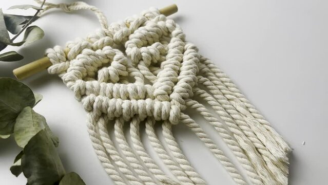 Macram&eacute; wall hanging,  with heart pattern. close up. Slow motion shot. macrame pattern from natural white cotton threads. 