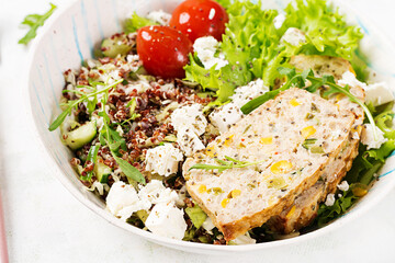 Healthy salad bowl with quinoa, tomatoes, chicken meatloaf and feta cheese on bowl. Food and health.