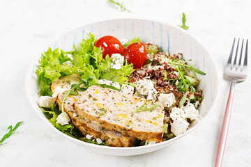 Healthy salad bowl with quinoa, tomatoes, chicken meatloaf and feta cheese on bowl. Food and health.