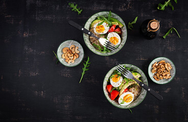 Breakfast oatmeal porridge with boiled eggs, avocado, tomatoes and green herbs. Healthy balanced food. Top view, flat lay