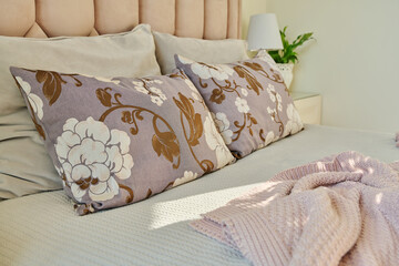 Cushions on bed close-up, in interior of classic bedroom in pink light ivory colors