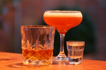 tow cocktails and a shot on a wooden surface