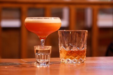 two cocktails and a glass of shot on a wooden surface