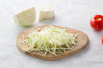Wooden board with shredded cabbage on a light gray background. Cooking healthy vegan food