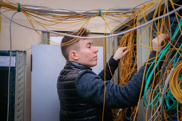 Technician switching fiber optic wires in the server room. The guy works with a lot of cables in...