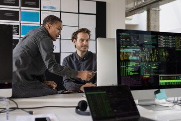 Coders working together at a desktop computer in an office