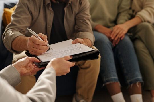 Close-up of man signing custody contract during a meeting with social worker at home