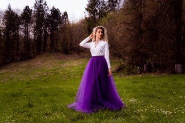 Obraz na płótnie Canvas Fashionable young woman wearing a long purple skirt a forest