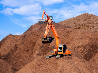 Pile of wood chips to storage for export by backhoe