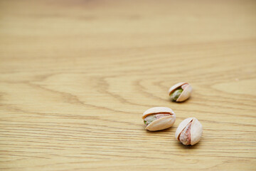 Pistachio nuts on a wooden table. Pistachios background close-up, place for text.