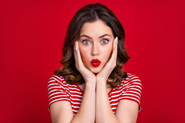 Portrait of shocked speechless girl hands touch cheekbones pouted lips cant believe isolated on vivid red color background