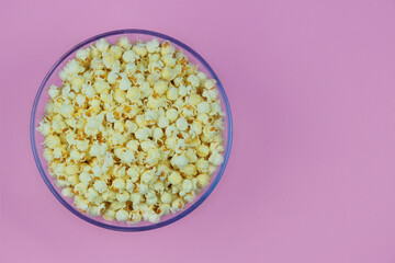 Popcorn large bowl on a pink background. Fast food for cinema. Top view.