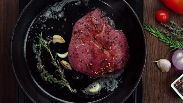 Pork steak fried in a pan with rosemary and garlic