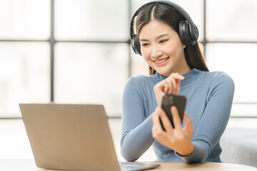 Beautiful smiling young woman in headphones chatting via laptop computer video call at home