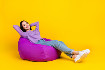 Full size photo of cheerful girl bob hairdo violet shirt pants sit on pouf hold hands behind head...