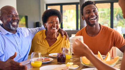 Family Shot With Senior Parents And Adult Offspring At Breakfast Around Table At Home