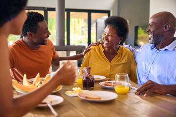 Family Shot With Senior Parents And Adult Offspring At Breakfast Around Table At Home