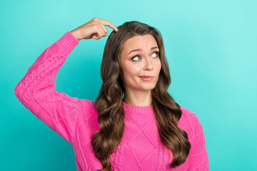 Photo of doubtful unsure girl wear pink sweater finger head looking empty space isolated turquoise color background