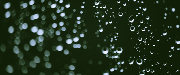 Atmospheric minimal monochrome backdrop with rain droplets on glass. Wet window with rainy drops and dirt spots closeup. Blurry minimalist background of dirty window glass with raindrops close up.