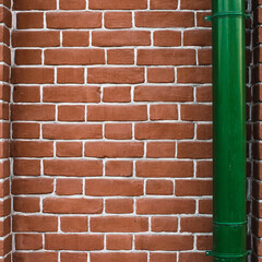 Minimalist fragment of brick wall with downspout close up. Beautiful brick backdrop with drain pipe. Geometric and symmetrical background of brick wall pattern. Modern design of interior or exterior.