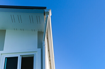 House roof with rain gutter of roof top house and large windows on blue sky background, New modern building