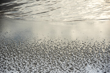 Cracked ice on a frozen lake. The natural texture of winter ice with white bubbles and cracks on a frozen lake.