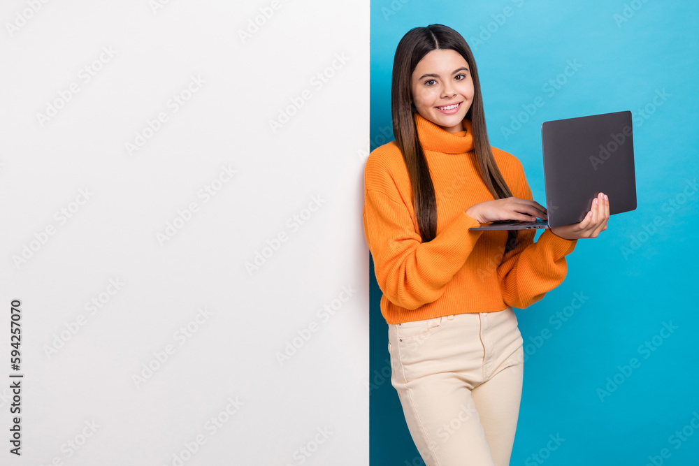 Wall mural photo of satisfied girl straight hairdo wear orange sweater hold laptop stand near empty space billb