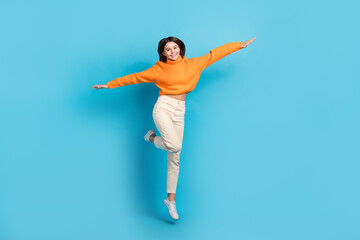 Fototapeta na wymiar Full body portrait of crazy overjoyed person jumping arms wings flying isolated on blue color background