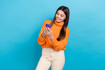 Photo of positive nice girl use smart phone chatting typing blog post isolated on blue color...