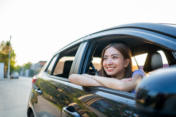 Young beautiful asian women getting new car. she very happy and excited. Smiling female driving vehicle on the road on a bright day.