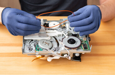 a man repairs and solders microcircuits for household appliances