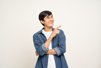 Handsome young man age around 25 smiling and happy pointing copy space. Charming male standing with on isolated white background. Asian people pose  with white backdrop.