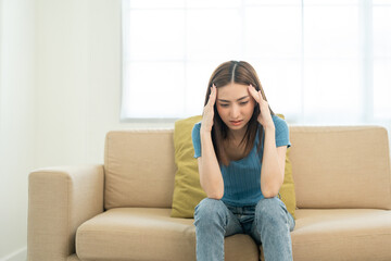 Depressed and Stressed asian woman on sofa. Crying sadness female alone in home problem in life. Unhappy asian woman headache Upset frustrated by problem love relationship feeling despair and anxiety